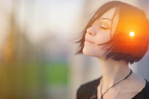 Double multiply exposure portrait of a woman meditating outdoors with eyes closed, combined with photograph of nature, sunrise or sunset, closeup. Psychology freedom power of mind concept